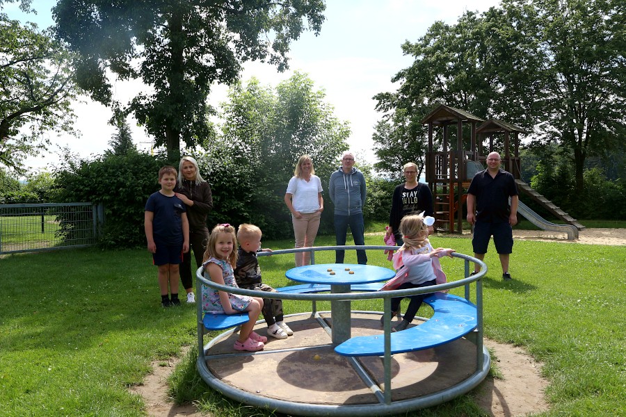 Lenox und Ina Hoppe, Catarina und Marco Rabeneick und Sandra Hechler (von links) haben mit Ratsmitglied Dennis Jorczick besprochen, wie und auf welchem Weg der Spielplatz Nienhagen auch für ganz kleine Kinder und ihre Eltern attraktiv gemacht werden könnte. Marie, Milan und Luisa probieren das Karussell aus. Foto: Thomas Dohna