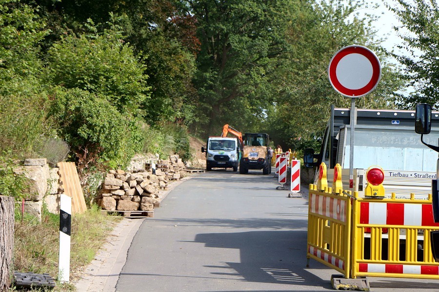 Die Bauarbeiten für die Trockenmauer an der Dorfstraße in Greste ist der Grund für die Sperrung der Straße. Ihre Steine sind auf Paletten gestapelt. Foto: Thomas Dohna