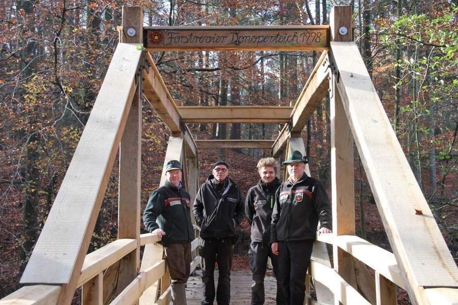 Freuen sich über die fertiggestellte und „echt lippische“ Fußgängerbrücke am Hasselbachstausee (v.l.n.r.): Stefan Schreiber, Leiter des Forstreviers Hiddesen, Andreas und Julius Brandt von Holzbau Brandt sowie Hans-Ulrich Braun, Leiter der Forstabteilung beim Landesverband Lippe. (Foto: Landesverband Lippe)