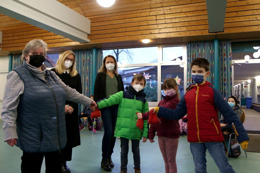 Birgitt Psiorz (links) von der Tafel Leopoldshöhe erhält von Niklas, Lina und Jona drei rote Säckchen. Darin ist Geld, das die Kinder innerhalb von zwei Jahren gesammelt haben. Manuela Knoche und Schulleiterin Diana Fleer schauen zu. Foto: Thomas Dohna