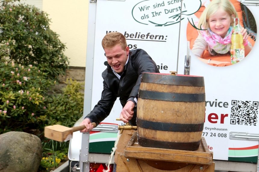Jan Meier zu Evenhausen schlägt mit Schwung auf den Bierhahn, um ihn ins Fass zu treiben. Foto: Thomas Dohna