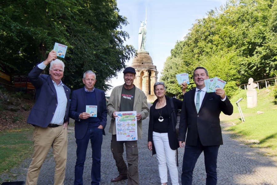 Manfred Hütte (Kurier-Verlag), Dr. Albert Hüser (Lippischer Heimatbund), Zeichner Mark Schäferjohann, Annette Paschke-Lehmann (Landesverband) und Landrat Dr. Axel Lehmann (von links) präsentierten die Neuauflage der ersten Ausgabe von "Hermännchen unterwegs in Lippe" am Hermannsdenkmal. Foto: Kreis Lippe.