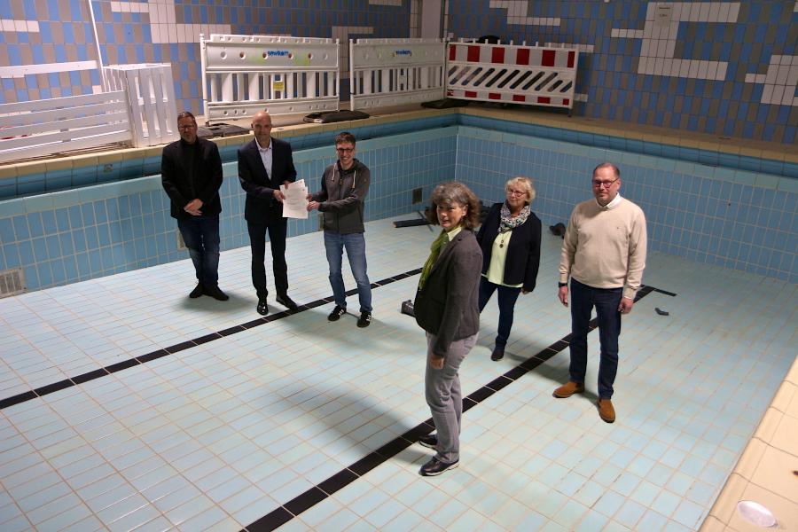 Architekt Falko Biermann (von links), Jens Kronsbein von der Bezirksregierung Detmold, Bürgermeister Martin Hoffmann, Stadtplanerin Susanne Knipping, Schulleiterin Cornelia Schmidt und Fachbereichsleiter Dirk Puchert-Blöbaum stehen im leeren Becken des Lehrschwimmbades der Grundschule Nord. Es soll saniert werden. Kronsbein überreicht Hoffmann den Förderbescheid über 2,3 Millionen Euro. Foto: Thomas Dohna