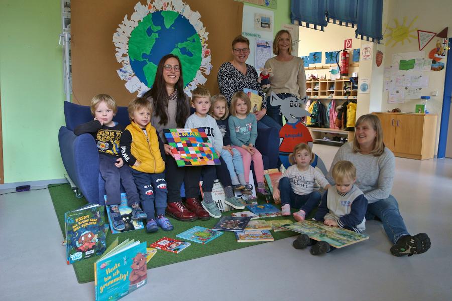 Kerstin Koppmann, Leiterin der Gemeindebücherein sitzt mit Hanno (von lonks), Nick, Hannes, Nora und Lena suf dem Vorlesesofa der Kita Greste. Die Bücherei-Mitarbeiterinnen Kerstin Pröpper (links) und Bettina Bentling stehen dahinter. Erzieherin Ute Piepenbrink sitzt mit Jana und Oliver davor. Ausgebreitet sind die Bücher, die die Gemeindebücherei an die Kita ausgeliehen hat. Foto: Thomas Dohna