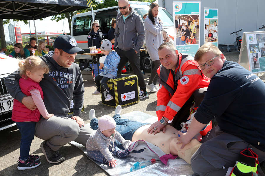 Tobias Bittner (zweiter von rechts) und Tjark Fichtner (rechts) vom DRK demonstrieren an einer Gummipuppe Wiederbelebungsmaßnahmen. Lea ( links) ist beeindruckt. Vater André Schaaf und Schwester Leonie schauen ebenfalls zu. Foto: Edeltraud Dombert.