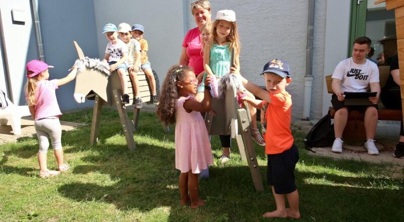 Kita-Leiterin Bianca Prüßner steht mit einigen Kindern der Kita an den neuen Eseln für die Kita am Eselsbach. Foto: Thomas Dohna