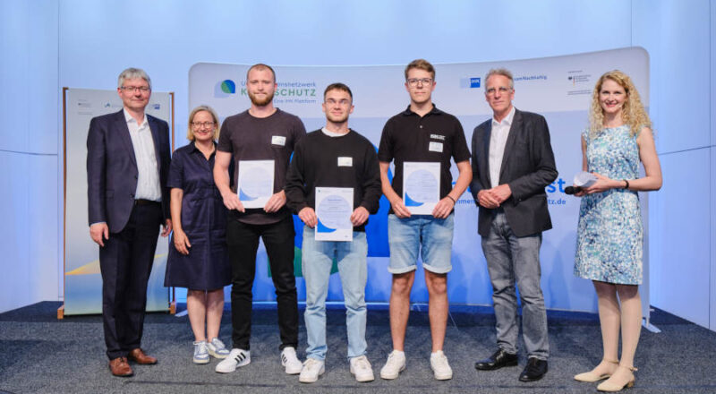 Eine besondere Auszeichnung für eine besondere Idee: Mit Dennis Wedel, Alexander Hartmann, Fynn Kaspar (3., 4. und 5. v.l.) freuen sich (v.l) Achim Derks (stv. Hauptgeschäftsführer DIHK), Anke Schweda (IHK Osnabrück),), Stefan Wenzel (Parlamentarischer Staatssekretär des BMWK) und Moderatorin Lis Blume mit den Preisträgern. Quelle: DIHK
