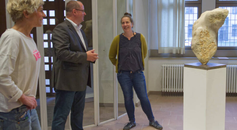 Carolin Engels (rechts) präsentiert Arne Brand (Allg. Vertreter des Verbandsvorsteher) und Vera Scheef (Lippische Kulturagentur) ihre aus Thüster Kalkstein entstandene Skulptur. Foto: LVL