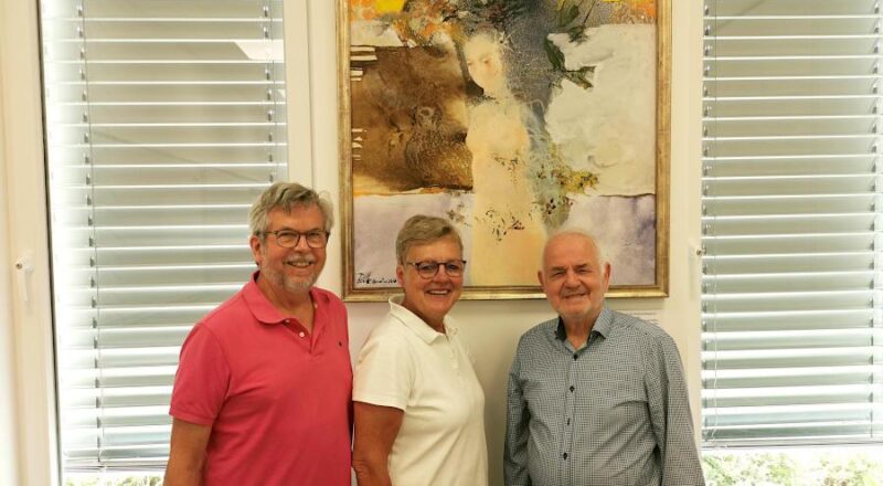 Axel Zander, Heike Kortekamp (1. Vorsitzende des Partnerschaftsvereins) und der Künstler Redzep Memisevic stehen vor dem Bild „Nach dem Bade", das ab sofort im Raum "St. Gaultier" im Begegnungszentrum B-vier in Asemissen hängt. Foto: Privat