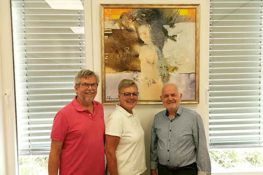 Axel Zander, Heike Kortekamp (1. Vorsitzende des Partnerschaftsvereins) und der Künstler Redzep Memisevic stehen vor dem Bild „Nach dem Bade", das ab sofort im Raum "St. Gaultier" im Begegnungszentrum B-vier in Asemissen hängt. Foto: Privat