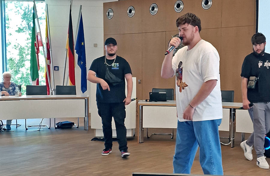 „Rebellion“ im Kreistagssitzungssaal: Almir, Jeremy und Amir (von links) performen ihren Rapsong, der auch von Brigitte van Ahee von den „Omas gegen Rechts“ (hinten links) begeistert verfolgt wurde. Foto: Kreis Lippe