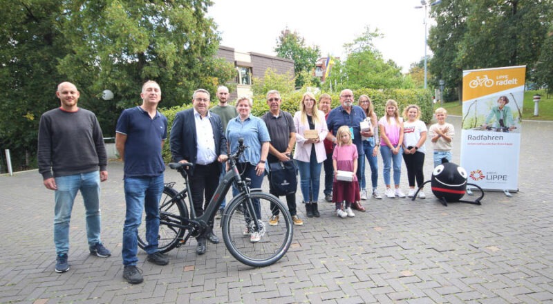 Dennis Hetmann, Mobilitätsmanager des Kreises Lippe, Niels Homann, Gewinner des Pedelecs, Landrat Dr. Axel Lehmann, Christian Bange und Anna-Lena Mügge, Radverkehrsbeauftrage des Kreises Lippe, Karsten Krull, Christine Fricke, Tobias Hempelmann, Walter Reese mit Enkelin und Lehrerin Sandra Völkner mit Schülerinnen und Schüler der Gewinnerklasse der Städtischen Realschule im Schulzentrum Aspe sowie das Maskottchen der Europäischen Mobilitätswoche freuen sich über die Preisverleihung. Foto: Kreis Lippe