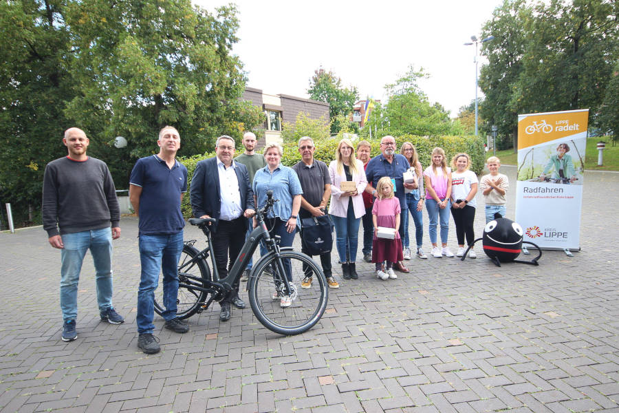 Dennis Hetmann, Mobilitätsmanager des Kreises Lippe, Niels Homann, Gewinner des Pedelecs, Landrat Dr. Axel Lehmann, Christian Bange und Anna-Lena Mügge, Radverkehrsbeauftrage des Kreises Lippe, Karsten Krull, Christine Fricke, Tobias Hempelmann, Walter Reese mit Enkelin und Lehrerin Sandra Völkner mit Schülerinnen und Schüler der Gewinnerklasse der Städtischen Realschule im Schulzentrum Aspe sowie das Maskottchen der Europäischen Mobilitätswoche freuen sich über die Preisverleihung. Foto: Kreis Lippe