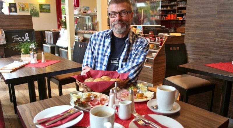 Thorsten Bökenbrink sitzt an einem Tisch, den er für Gäste gerade gedeckt hat. Seit fünf Jahren betreibt er das Café Fahrzeit. Foto: Thomas Dohna