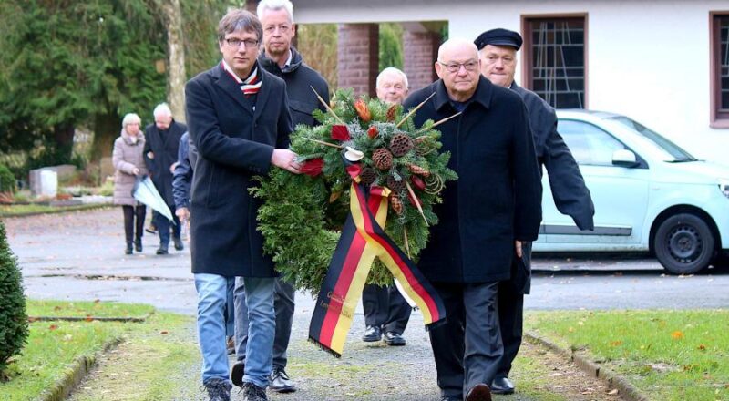 Bürgermeister Martin Hoffmann (links) und sein Stellvertreter Klaus Fiedler tragen einen Kranz zum Ehremal auf dem Dalhauser Friedhof. Dahinter tragen Klaus Sunkovsky (links, Gemeindeverwaltung) und der stellvertretende Bürgermeister Andreas Brinkmann eine weiteren Kranz. Foto: Thomas Dohna