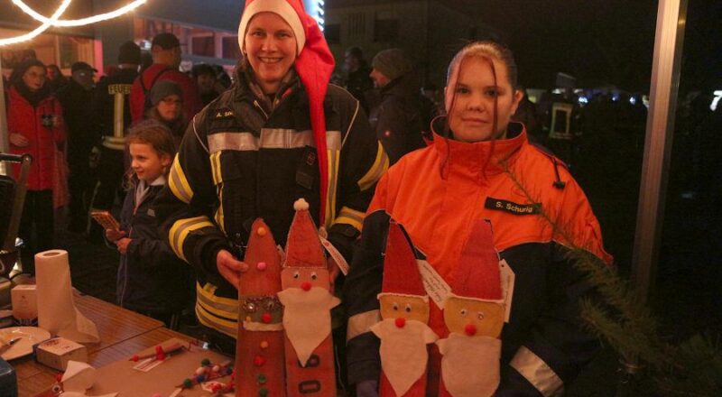 Jugendwartin Andrea Stölting (links) und Sarah-Lee Schurig zeigen, was sie am Stand der Jugendfeuerwehr anbieten: aus alten Schläuchen gebastete Weihnachtsmänner. Foto: Thomas Dohna