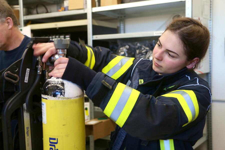 In der Atemschutzwerkstatt schraubt Julie Schütze eine frische Druckluftflasche an das Gerät. Foto: Thomas Dohna