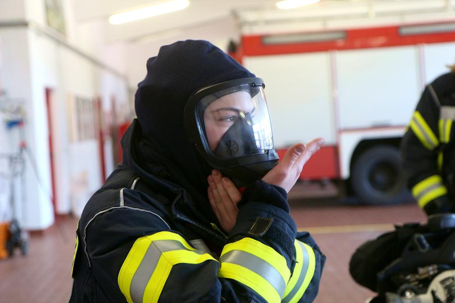 Julie Schütze prüft, ob die Maske dicht sitzt, in dem sie den Atemanschluss dicht hält und einatmet. Foto: Thomas Dohna