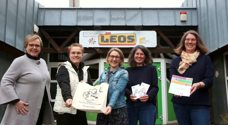 Ute Küstermann (Kreis Lippe, von links), Lena Hoffmann (Familienbeauftragte DRK), Astrid Möller (DRK SPROSS), Sandra Linnenbecker (Familienservicebüro Leos) und Andrea Rodekamp (Gemeindeverwaltung Leopoldshöhe) zeigen Logo, Beutel und Broschüren des Familienbesuchsdienstes SPROSS vor. Foto: Thomas Dohna