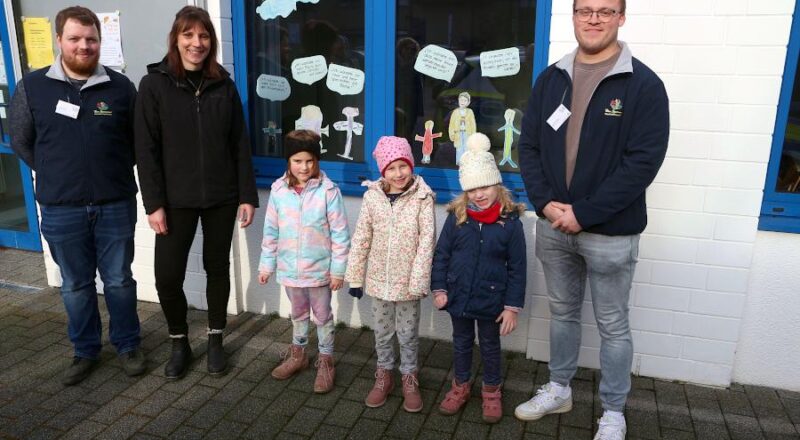 Jonas Droste (von links) von der Kita Spatzennest, Mutter Sarah Landermann, diue Kinder Svea, Liske und Julia sowie Yannik Bilke (Kita Spatzennest) stehen vor dem Fenster, das Kinder der Kita Spazennest gestaltet haben. Foto: Thomas Dohna