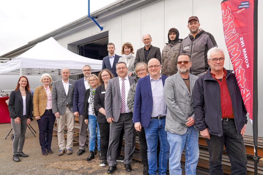 Freuen sich über den gelungenen Start des Projekts „Übergangslotsen“: Christian Zimmermann (Arbeitsvermittler bei der Agentur für Arbeit Detmold, hinten von links), Dr. Martina Schwartz-Gehring (Vorstandsvorsitzende der Osthushenrich-Stiftung), Rainer Radler (Leitung der Agentur für Arbeit Detmold), Auszubildender Abubaker El Kahloun Amar, Heiko Prause (Inhaber von Heiko Prause HPK-Metallbau) und Vanessa Boschke (Koordinierungsstelle Schule-Beruf, vorne von links), Claudia Holle (Geschäftsführerin der Osthushenrich-Stiftung), Stefan Susat (Vorstand des Jobcenters Lippe), Heiko Jucks (Schulleitung des Hanse-Berufskollegs), Claudia Eikmann (Bezirksregierung Detmold), Übergangslotsin Nadja Steinhage, Landrat Dr. Axel Lehmann, Übergangslotsin Heike Görder, Dirk Menzel (Vorstand der Lippe Bildung eG) sowie die Übergangslotsen Sebastian Strothenke und Ulrich Kell. Foto: Kreis Lippe