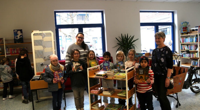 Die OGS-Mitarbeiterinnen der Grundschule Nord Bettina Wagner (rechts) und Alina Weber haben mit den Kindern des Lese-Projektes viele Kinderbücher ausgesucht und auf den Rollwagen gelegt. Foto: Edeltraud Dombert