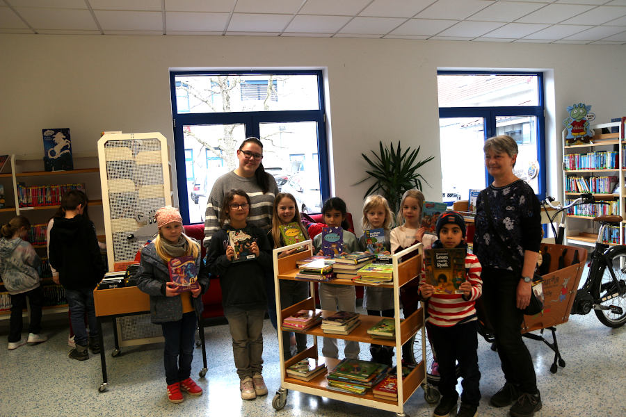 Die OGS-Mitarbeiterinnen der Grundschule Nord  Bettina Wagner (rechts) und Alina Weber haben mit den Kindern der Lese-AG viele Kinderbücher ausgesucht und auf den Rollwagen gelegt. Foto: Edeltraud Dombert