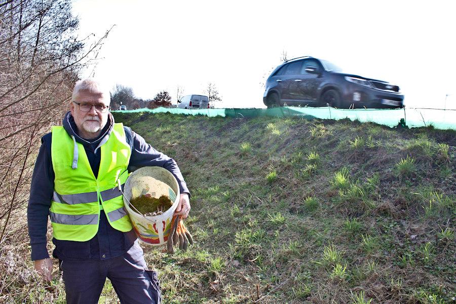 Dirk Rosenlicht steht mit einem Eimer unter dem Arm an der Bielefelder Straße. Oben an der Straße verläuft ein Krötenschutzzaun. Foto: Thomas Dohna