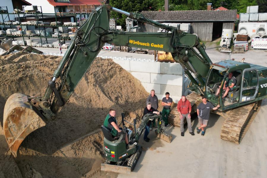 Ein Teil der Belegschaft der Wiebusch GmbH hat sich an dem größten und dem kleinsten Bagger des Betriebes aufgestellt. Foto: Wiebusch GmbH