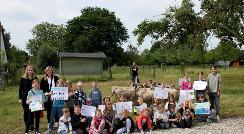 Kinder vom Schülerparlament der Grundschule Asemissen und die Kinder der Klasse 2b der Grundschule Nord präsentieren mit ihren Lehrerinnen Manuela Knoche (dritte von links), Annika Nähler (rechts) und Referendarin Sarah Liehr (links) ihre selbstgefertigten Plakate. Im Hintergrund überwacht Pia Völker ihre Schafherde. Foto: Edeltraud Dombert