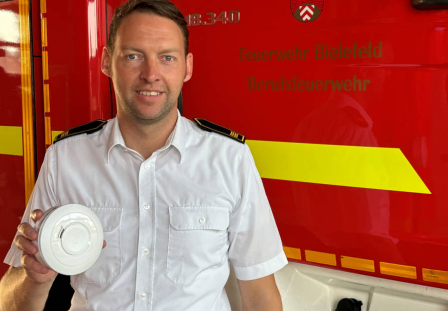 Maximilian Rempe, bei der Feuerwehr Bielefeld zuständig für den Vorbeugenden Brandschutzt, mit einem Rauchmelder. Foto: Stadt Bielefeld