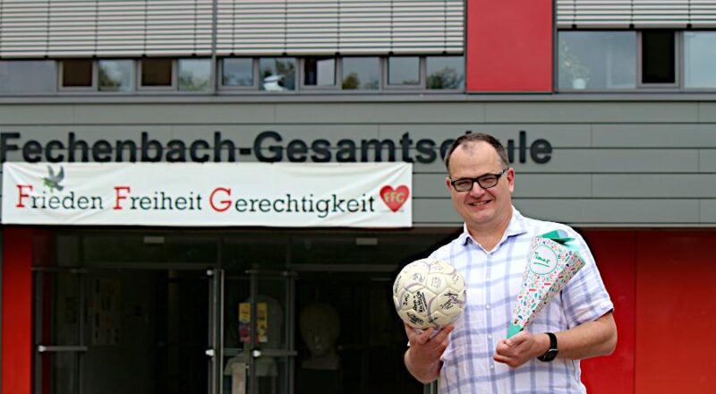 Thomas Friebertshäuser ist der neue Leiter der Felix-Fechenbach-Gesamtschule. Er hält einen Fußball in der Hand, auf dem die Schülerinnen und Schüler seines ersten Mathekurses an der Gesamtschule Lemgo unterschrieben haben und eine Schultüte, die ihm das Kollegium der FFG zum Einstieg überreicht hat. Foto: Thomas Dohna