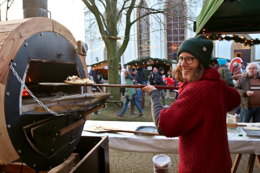 Svenja Düning beschickt den Holzofen, in dem die Aktiven der Kirchengemeinde Leckereien buken. Foto: Thomas Dohna