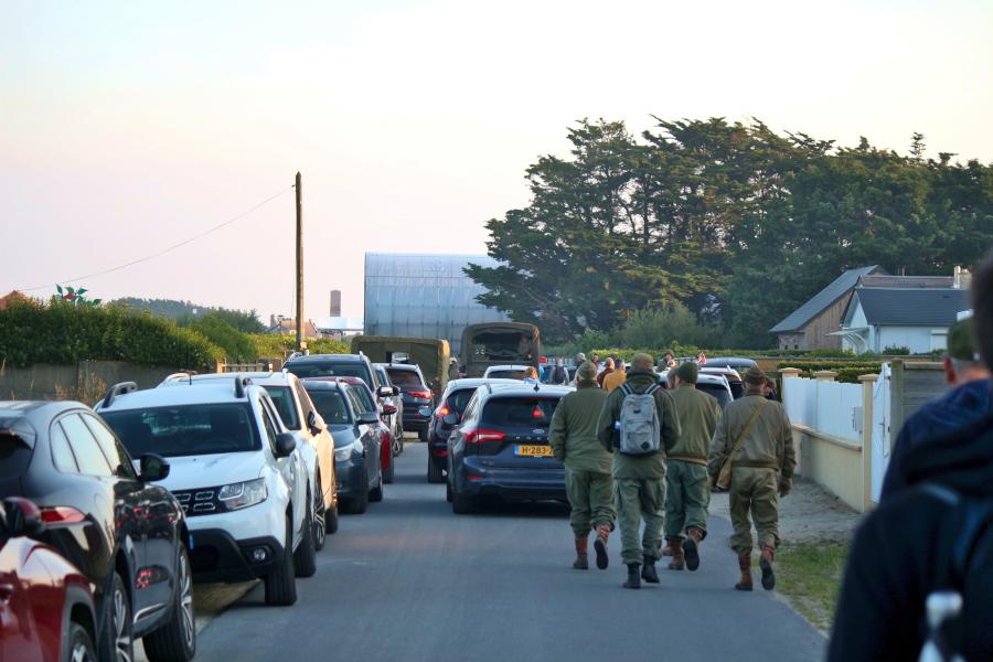 Inmitten moderner Autos laufen als alliierte Soldaten des Zweiten Weltkriegs verkleidete Männer in Richtung Utah Beach. Foto: Thomas Dohna