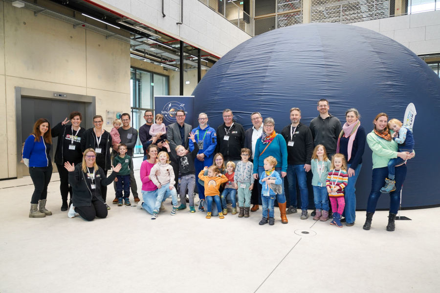 Vorfreude auf die erste Planetariums-Vorführung: Kitakinder, Eltern und Mitarbeitende des MINTmachCLUB.Lippe mit Landrat Dr. Axel Lehmann (6. v.r.) und Astrophysiker Tilo Hohenschläger (8. v.l.) vor dem mobilen Planetarium. Mit dabei: Marc Thiel (Geschäftsführung Lippe Bildung eG, 7. v.l.), Caroline Adolph (4. v.l.), Thomas Mahlmann (7. v.r.), Nadine Siekmeier (3. v.l.) Nadine Tober (2. v.l.), Oliver Hülsmann (4. v.r.), alle Lippe Bildung eG. Foto: Lippe Bildung e.G.