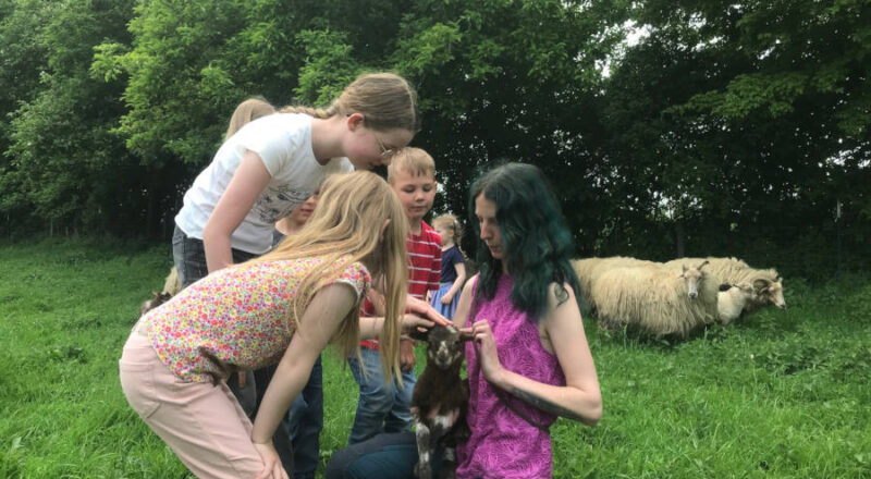 Pia mit James auf dem Arm wird von den Kindern umringt, die das Lamm gern streicheln möchten. Foto: Heimatverein