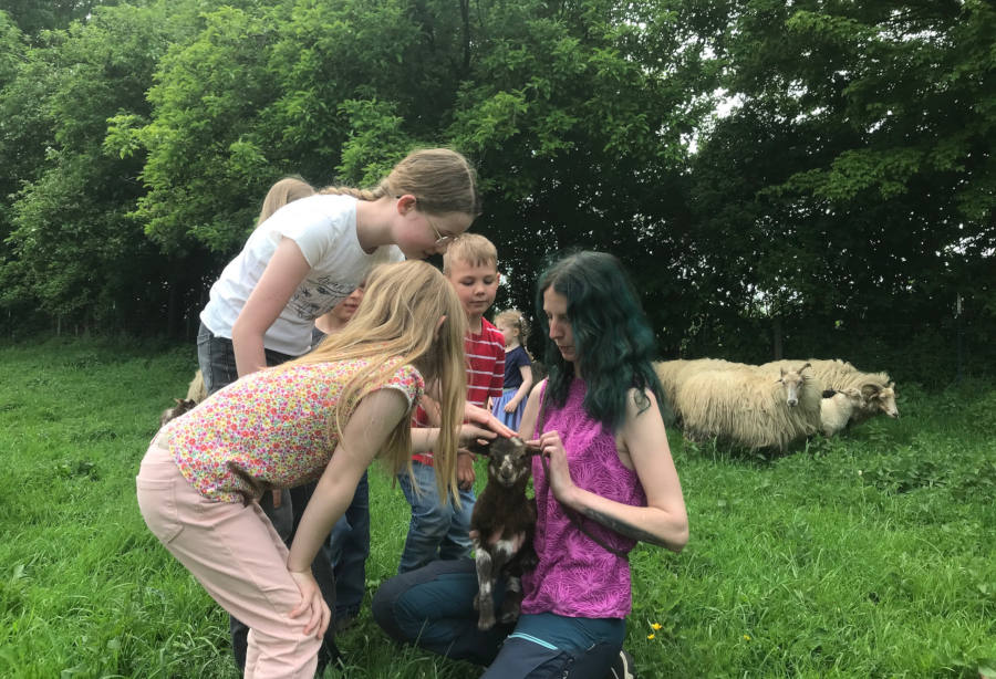 Pia mit James auf dem Arm wird von den Kindern umringt, die das Lamm gern streicheln möchten. Foto: Heimatverein