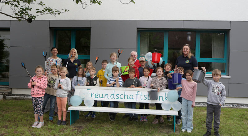 Die Kinder des Schülerparlamentes präsentieren vor der neuen Freundschaftsbank die frisch gekauften Greifzangen und Eimer für die Müllbeseitigung. Mit ihnen freut sich der Vorsitzende des Heimatvereins Helmut Depping und Vertreterinnen des Fördervereins der Grundschule Asemissen. Foto: Thomas Dohna