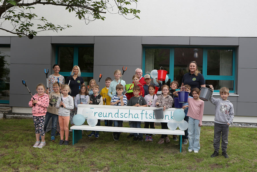 Die Kinder des Schülerparlamentes präsentieren vor der neuen Freundschaftsbank die frisch gekauften Greifzangen und Eimer für die Müllbeseitigung. Mit ihnen freut sich der Vorsitzende des Heimatvereins Helmut Depping und Vertreterinnen des Fördervereins der Grundschule Asemissen. Foto: Thomas Dohna