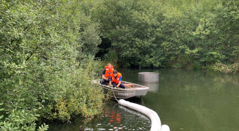 Feuerwehrleute bringen von einem Boot aus Ölschlengel auf dem Becken aus. Foto: Freiwillige Feuerwehr Leopoldshöhe