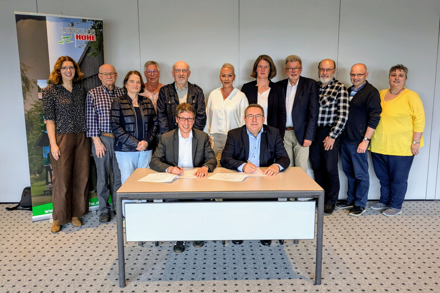 Landrat Axel Lehmann (vorn rechts) und Bürgermeister Martin Hoffmann unterzeichnen im Beisein der Kooperationspartner den SinfoL-Vertrag. Anna-Lena Bargfrede (Quartiersmanagerin, Gemeinde Leopoldshöhe, hinten von links.) Hans Koppmann (SoVD), Birgit Welter-Dahmen (Caritaskonferenz), Kornelia Siebert (Seniorenbeauftrage der Gemeinde Leopoldshöhe), Gerd Wolter (Soziales Netzwerk Leopoldshöhe), Michaela Flake (SinfoL-Projektbeauftragte, Kreis Lippe) Andrea Rodekamp (Gemeinde Leopoldshöhe), Gerhard Schemmel (AWO-Ortsverein Leopoldshöhe), Heinrich Klassen und Pastor Franz Peter (beide Mennonitengemeinde) sowie Bettina Rott (Gemeinde Leopoldshöhe). Foto: Gemeinde Leopoldshöhe