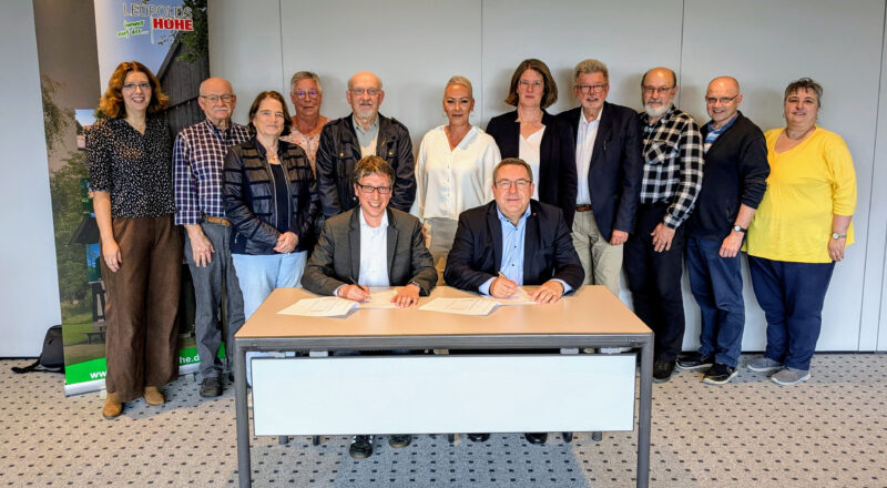 Landrat Axel Lehmann (vorn rechts) und Bürgermeister Martin Hoffmann unterzeichnen im Beisein der Kooperationspartner den SinfoL-Vertrag. Anna-Lena Bargfrede (Quartiersmanagerin, Gemeinde Leopoldshöhe, hinten von links.) Hans Koppmann (SoVD), Birgit Welter-Dahmen (Caritaskonferenz), Kornelia Siebert (Seniorenbeauftrage der Gemeinde Leopoldshöhe), Gerd Wolter (Soziales Netzwerk Leopoldshöhe), Michaela Flake (SinfoL-Projektbeauftragte, Kreis Lippe) Andrea Rodekamp (Gemeinde Leopoldshöhe), Gerhard Schemmel (AWO-Ortsverein Leopoldshöhe), Heinrich Klassen und Pastor Franz Peter (beide Mennonitengemeinde) sowie Bettina Rott (Gemeinde Leopoldshöhe). Foto: Gemeinde Leopoldshöhe