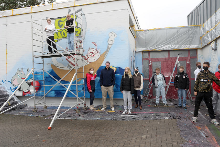 Zehn Jugendliche im Alter von zwölf bis 17 Jahren verschönern unter Anleitung des Künstlers Christoph Cornelius Kollmeier (vierter von links) drei Rückwände der Grundschule Nord. Foto: Edeltraud Dombert