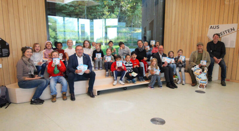 Dr. Ingo Möller (Leiter der KEW), Zeichner Mark Schäferjohann, Jörg-Düning Gast (Verbandsvorsteher des Landesverbands Lippe) und Landrat Dr. Axel Lehmann (vorn von rechts) haben der 2b des Grundschulverbunds Oerlinghausen mit ihrer Klassenlehrerin Ilona Schlüssel (links) das neue Hermännchen-Heft vorgestellt. Foto: Kreis Lippe