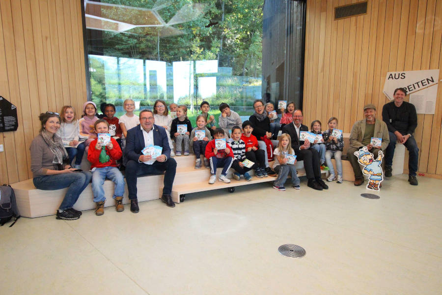Dr. Ingo Möller (Leiter der KEW), Zeichner Mark Schäferjohann, Jörg-Düning Gast (Verbandsvorsteher des Landesverbands Lippe) und Landrat Dr. Axel Lehmann (vorn von rechts) haben der 2b des Grundschulverbunds Oerlinghausen mit ihrer Klassenlehrerin Ilona Schlüssel (links) das neue Hermännchen-Heft vorgestellt. Foto: Kreis Lippe