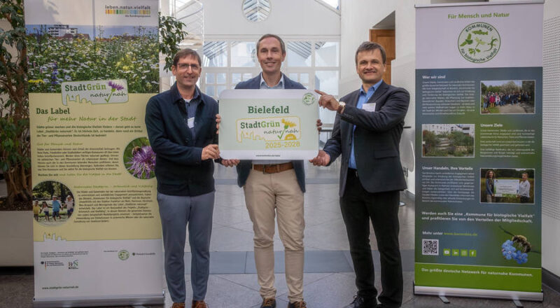 Sebastian Richter (Mitte), Leiter der Grünflächenunterhaltung im Umweltbetrieb, hat die Auszeichnung von Dr. Uwe Messer (links, Projektleiter Label Stadtgrün naturnah) und Robert Spreter (rechts, Geschäftsführer Kommbio) entgegengenommen. Foto: Stadt Bielefeld/UWB