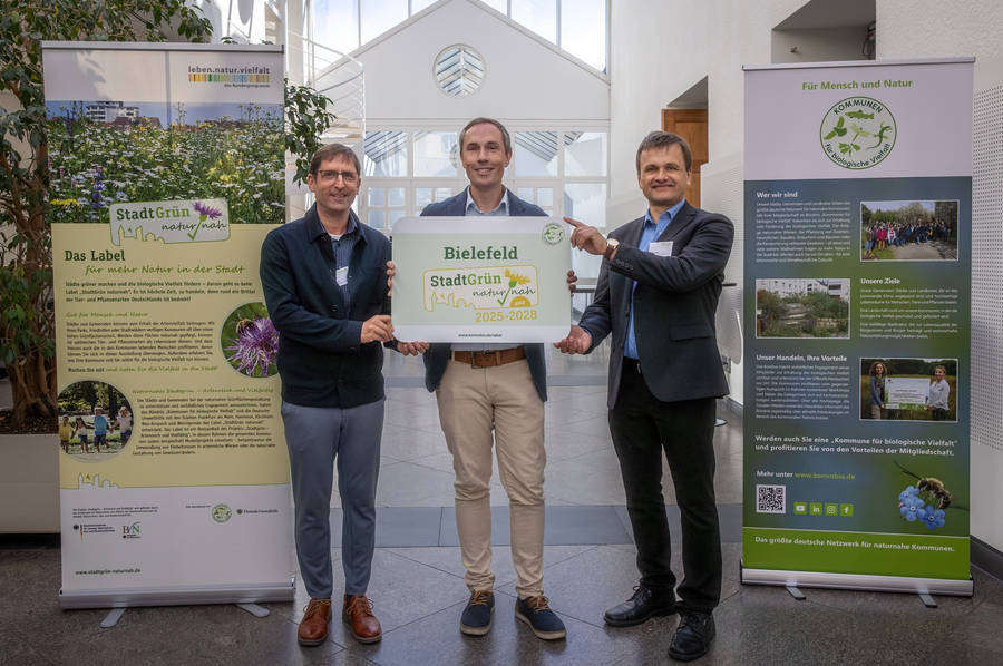 Sebastian Richter (Mitte), Leiter der Grünflächenunterhaltung im Umweltbetrieb, hat die Auszeichnung von Dr. Uwe Messer (links, Projektleiter Label Stadtgrün naturnah) und Robert Spreter (rechts, Geschäftsführer Kommbio) entgegengenommen. Foto: Stadt Bielefeld/UWB