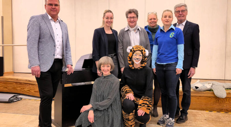 Pianistin Natalia Gamper (vorne, von links) und Streifentiger alias Professorin Claudia Runde (Musikhochschule Detmold) zauberten im Bürgerhaus Schlangen vor rund 350 Kindern der Grundschule Schlangen mit Tastentricks am Klavier. Mit dabei Bürgermeister Marcus Püster, Projektleiterin Delia Riedel, Geschäftsführerin Dr. A. Heinrike Heil (beide Stiftung Standortsicherung Kreis Lippe), Konrektorin Annette Brand, Rektorin Anne Schulz (beide Grundschule Schlangen) und Friedel Heuwinkel. Foto: Christina-Carolin Rempe/ Stiftung Standortsicherung
