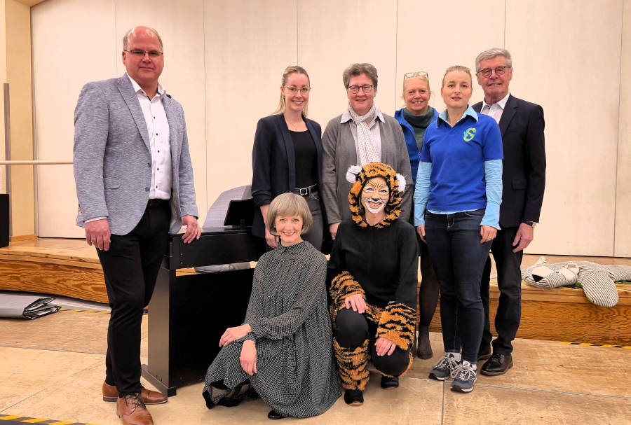 Pianistin Natalia Gamper (vorne, von links) und Streifentiger alias Professorin Claudia Runde (Musikhochschule Detmold) zauberten im Bürgerhaus Schlangen vor rund 350 Kindern der Grundschule Schlangen mit Tastentricks am Klavier. Mit dabei Bürgermeister Marcus Püster, Projektleiterin Delia Riedel, Geschäftsführerin Dr. A. Heinrike Heil (beide Stiftung Standortsicherung Kreis Lippe), Konrektorin Annette Brand, Rektorin Anne Schulz (beide Grundschule Schlangen) und Friedel Heuwinkel. Foto: Christina-Carolin Rempe/ Stiftung Standortsicherung