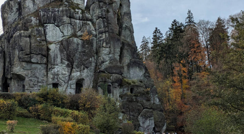 Bei herbstlicher Stimmung betrachtet eine Besuchergruppe das offene Felsengrab an den Externsteinen Foto:LVL